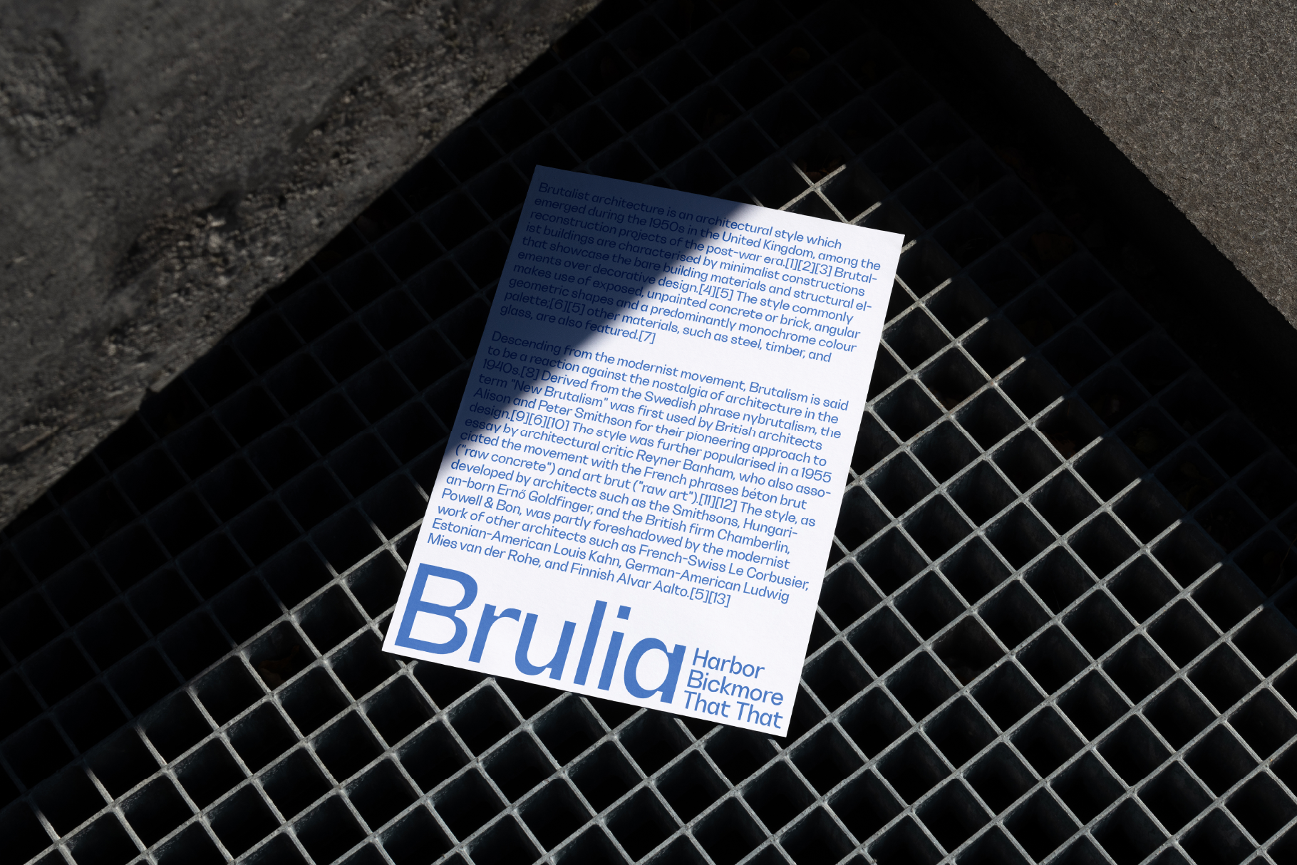 White card with blue text about Brutalism architecture lying on concrete grid