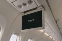 Blank airplane seatback screen in cabin with overhead air vents visible