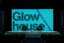 Stage backdrop in turquoise with dark Glow house text, two modern black seating chairs