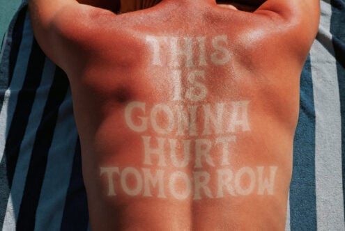 Sunburned back with text tan lines saying This is gonna hurt tomorrow on beach towel. Perfect for graphic design projects, summer-themed artwork, typography.