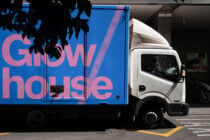 Blue truck panel with pink Glow house lettering silhouette leaves overhead