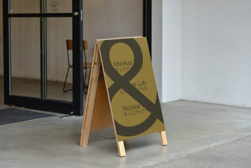 A-frame sign mockup outside a modern building with concrete floor and open glass door perfect for showcasing design graphics templates marketing materials.
