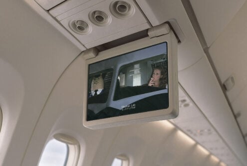 Airplane monitor mockup shows a retro movie with a man and woman in a cockpit. Ideal for aviation-themed design and graphic displays.
