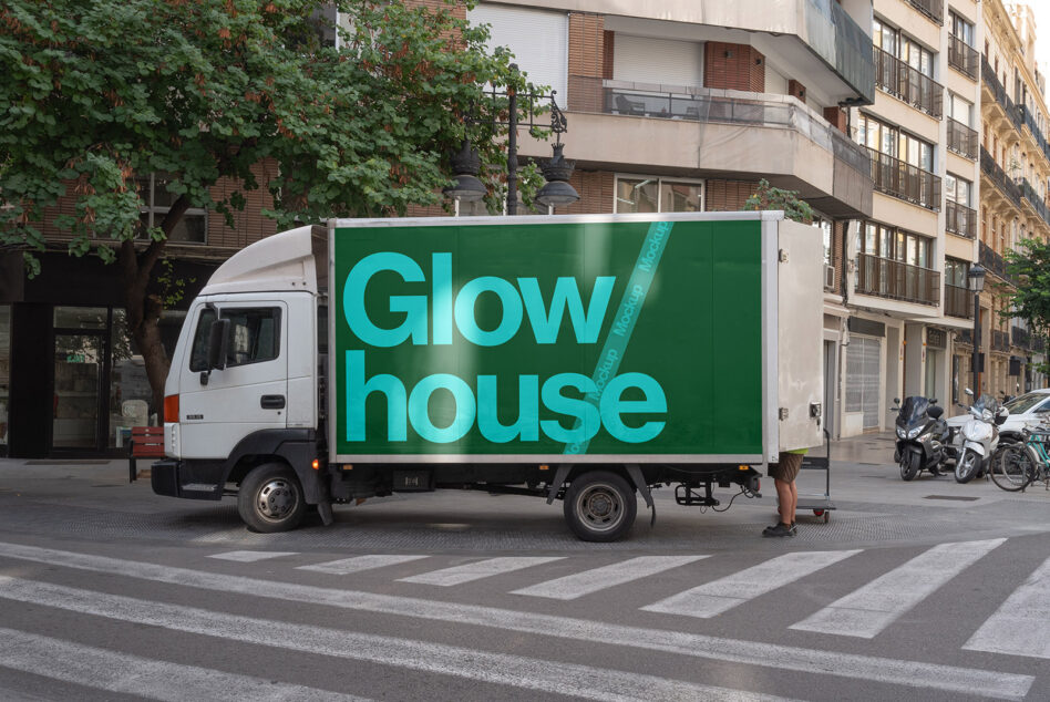 Delivery truck displaying cyan Glow house text on green background in urban street setting