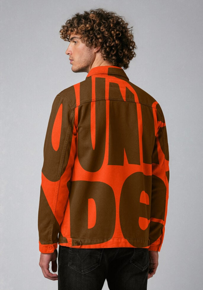 Man wearing bold graphic jacket with oversized letters, viewed from the back against a neutral background. Perfect for fashion mockup or design inspiration.