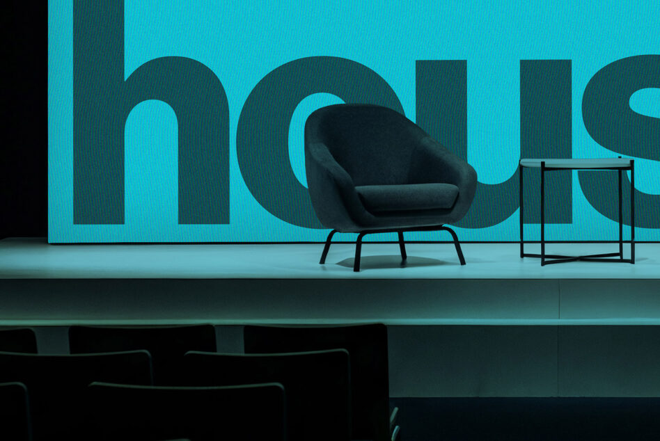 Modern stage setup with black armchair against bright cyan wall with cutout typography