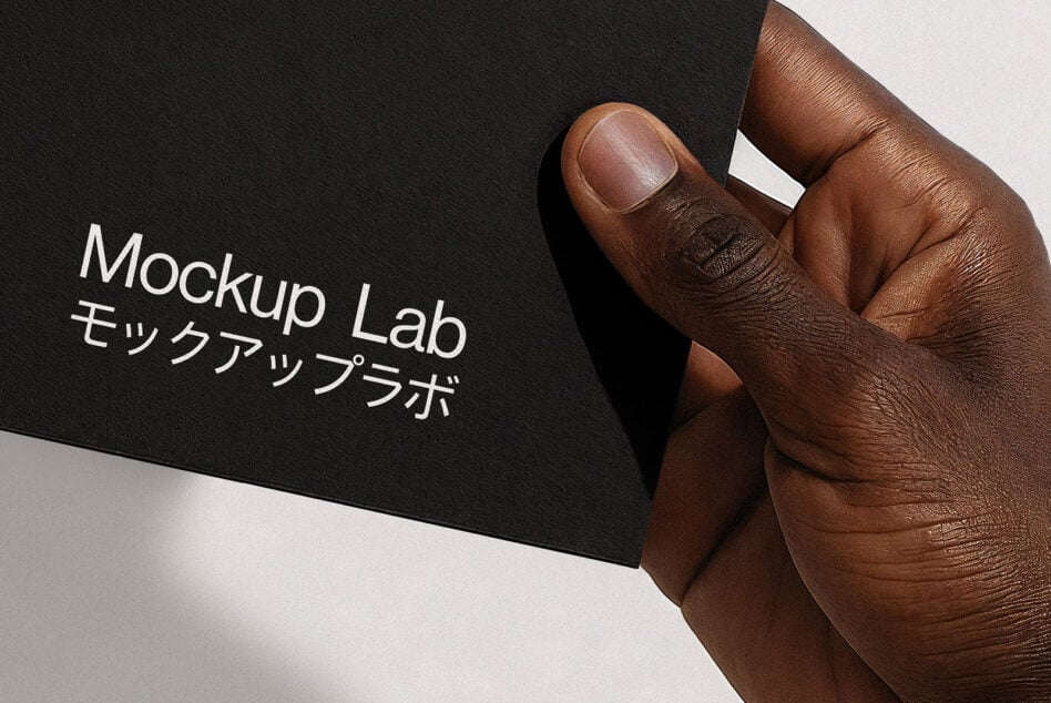Hand holding black business card with white text on textured paper