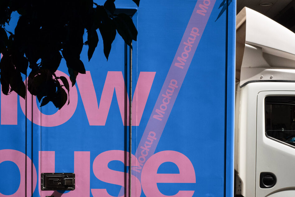 Close up of blue truck with large pink text partially visible with branch shadow