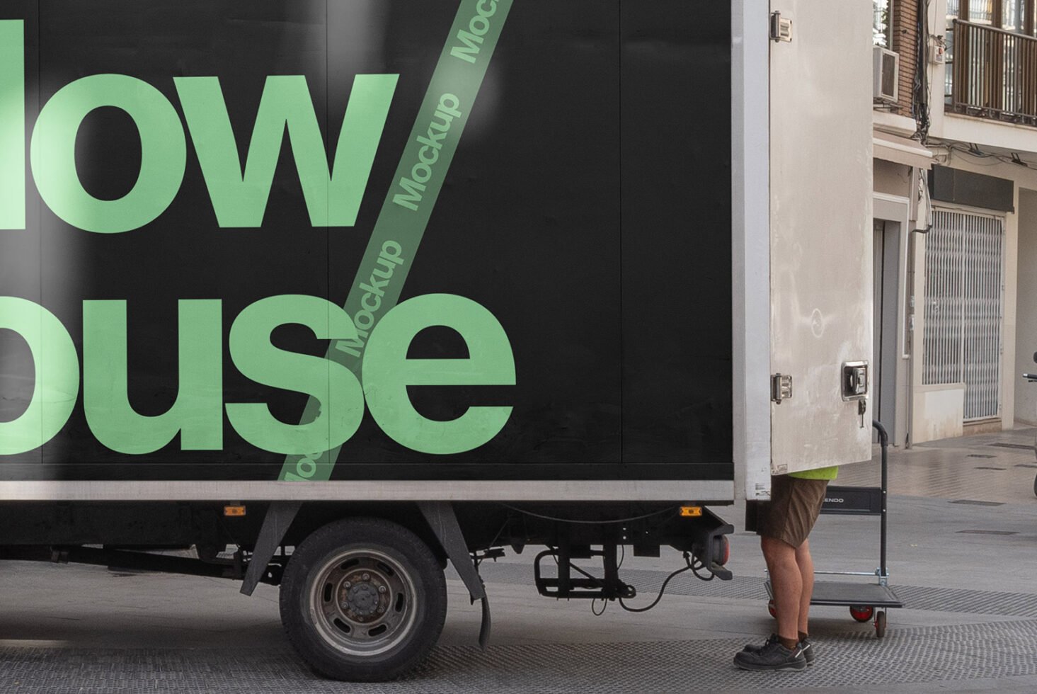 Truck side mockup in urban setting for designers featuring bold green text on black background. Ideal for showcasing branding or advertising designs.