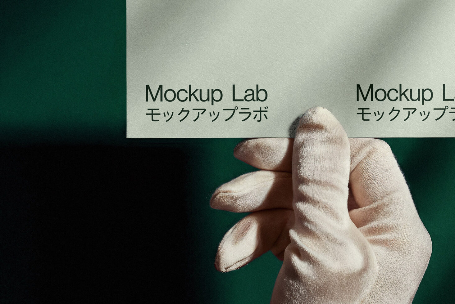 Gloved hand holding a textured paper with Mockup Lab text in Japanese and English, ideal for graphic designers seeking realistic branding mockup visuals.