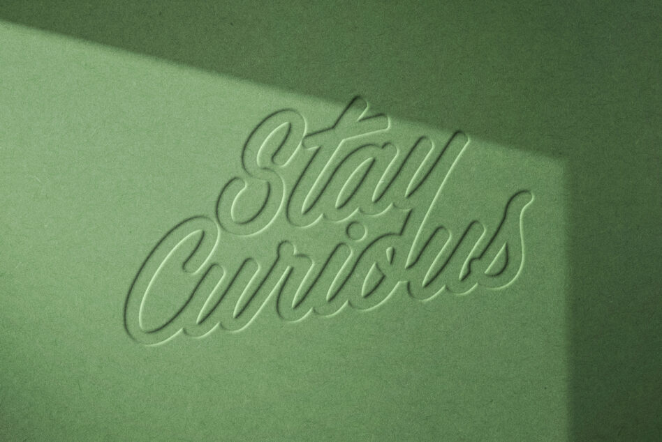 Embossed script text on matte green surface with directional light creating dimension