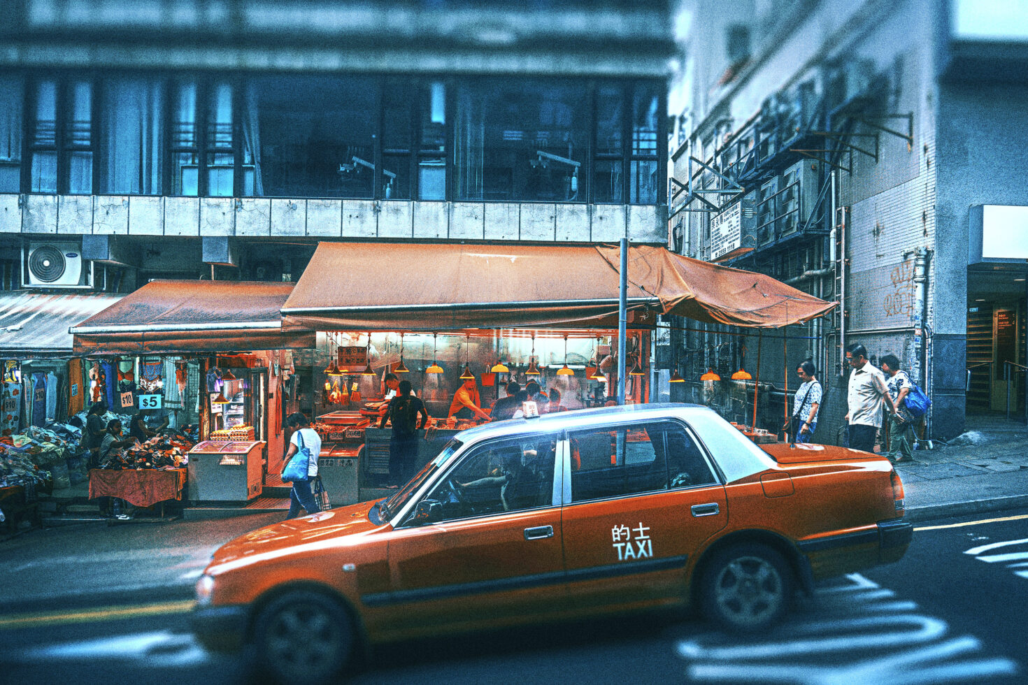 Urban street scene with an orange taxi passing by a vibrant market stall under an awning. Ideal for digital design, urban mockups, market graphics.