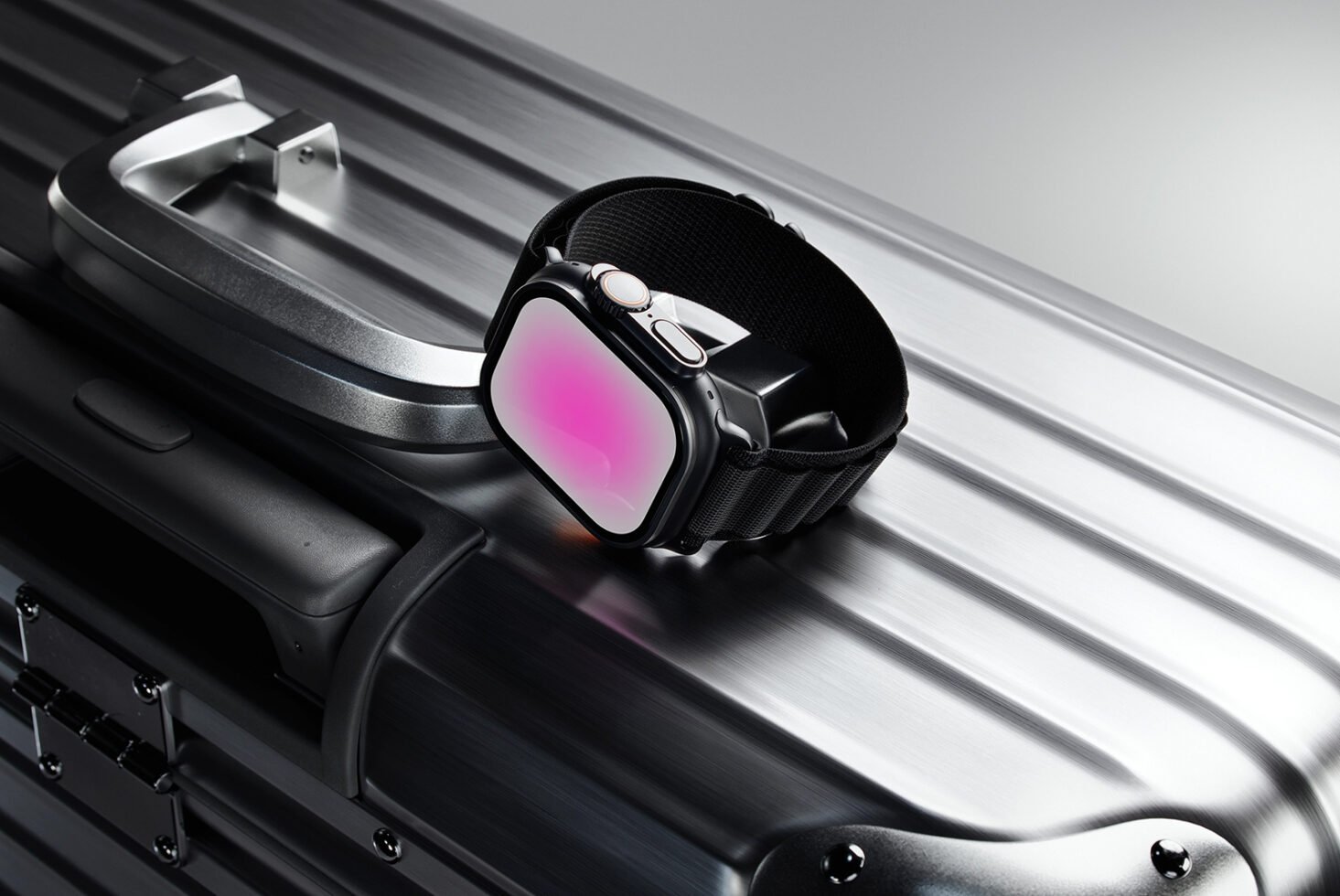 Smartwatch with a glowing pink screen placed on a sleek metallic suitcase. Modern tech mockup ideal for designers digital assets and graphic projects.