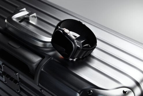 Smartwatch with black band resting on sleek silver suitcase, showcasing modern travel and fashion accessories. Ideal for designer mockups, templates.