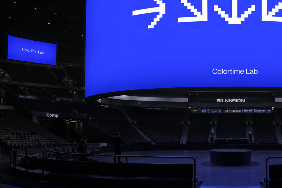 Large curved stadium screen displaying blue background with pixelated white numbers, Colortime Lab branding