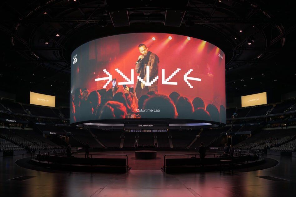 Arena jumbotron showing red concert performance with white pixelated text overlay, Colortime Lab logo
