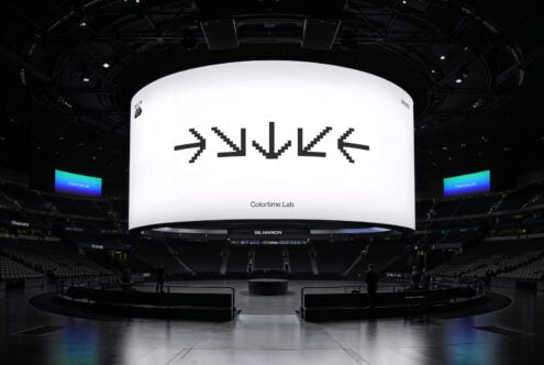Large digital screen in an arena displays pixel art arrows. Suitable for mockups or graphics needs in designer projects. Ideal for venue presentations.