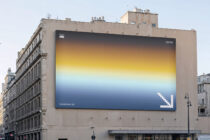 Large billboard on Paris building showing yellow-to-blue gradient with pixelated arrow icon
