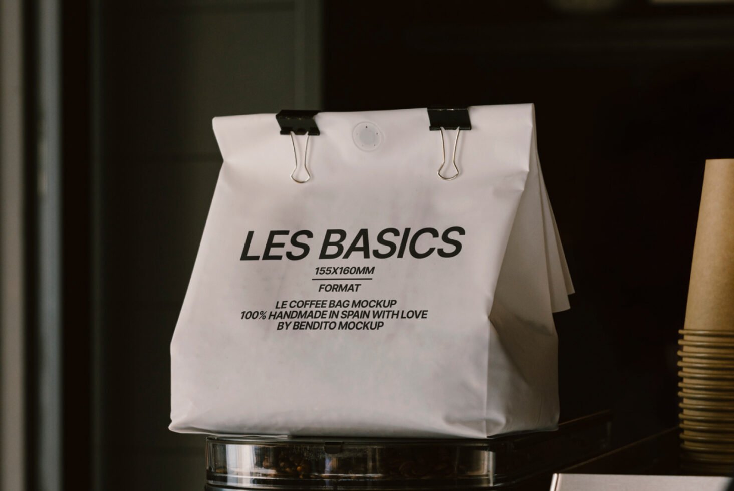 White coffee bag mockup with text Les Basics and binder clips. Design asset for packaging designers. Keywords: mockup, packaging, coffee bag, template.