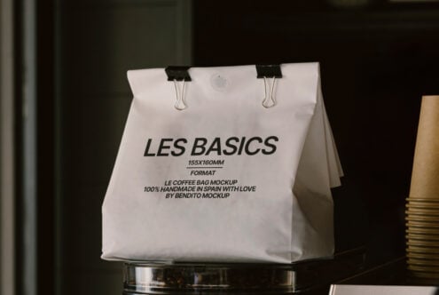 White coffee bag mockup with text Les Basics and binder clips. Design asset for packaging designers. Keywords: mockup, packaging, coffee bag, template.