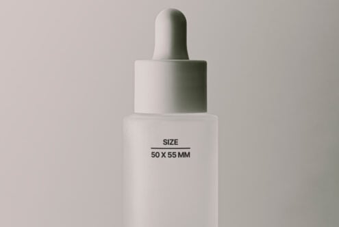 White dropper bottle with minimal cap stacked on pale background