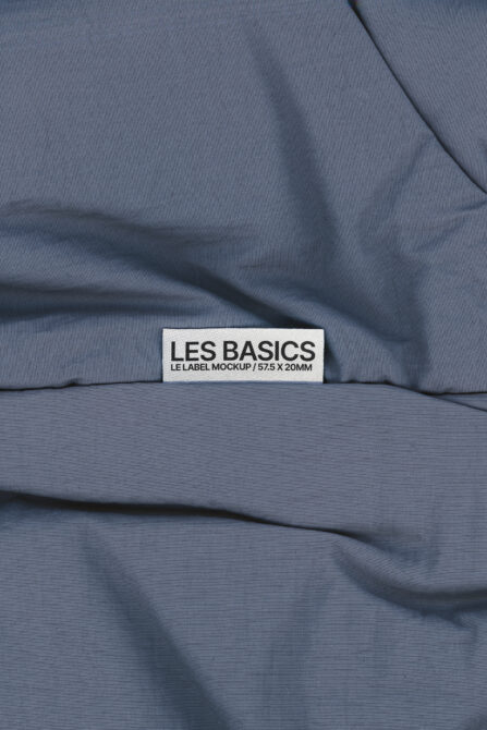 Les Basics woven tag on wrinkled blue fabric with gathered texture