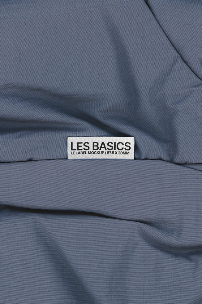 Les Basics woven tag on wrinkled blue fabric with gathered texture