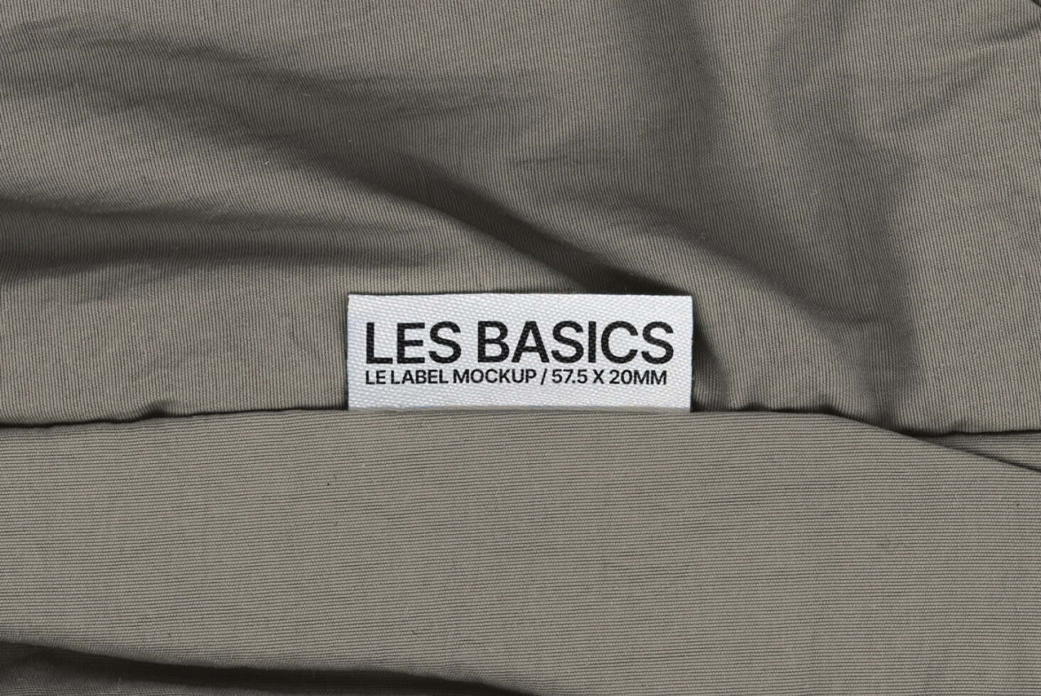 Les Basics woven label centered on draped gray fabric surface
