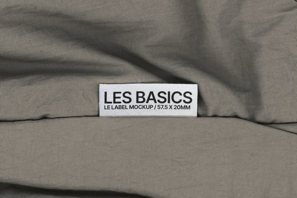 Les Basics woven label centered on draped gray fabric surface