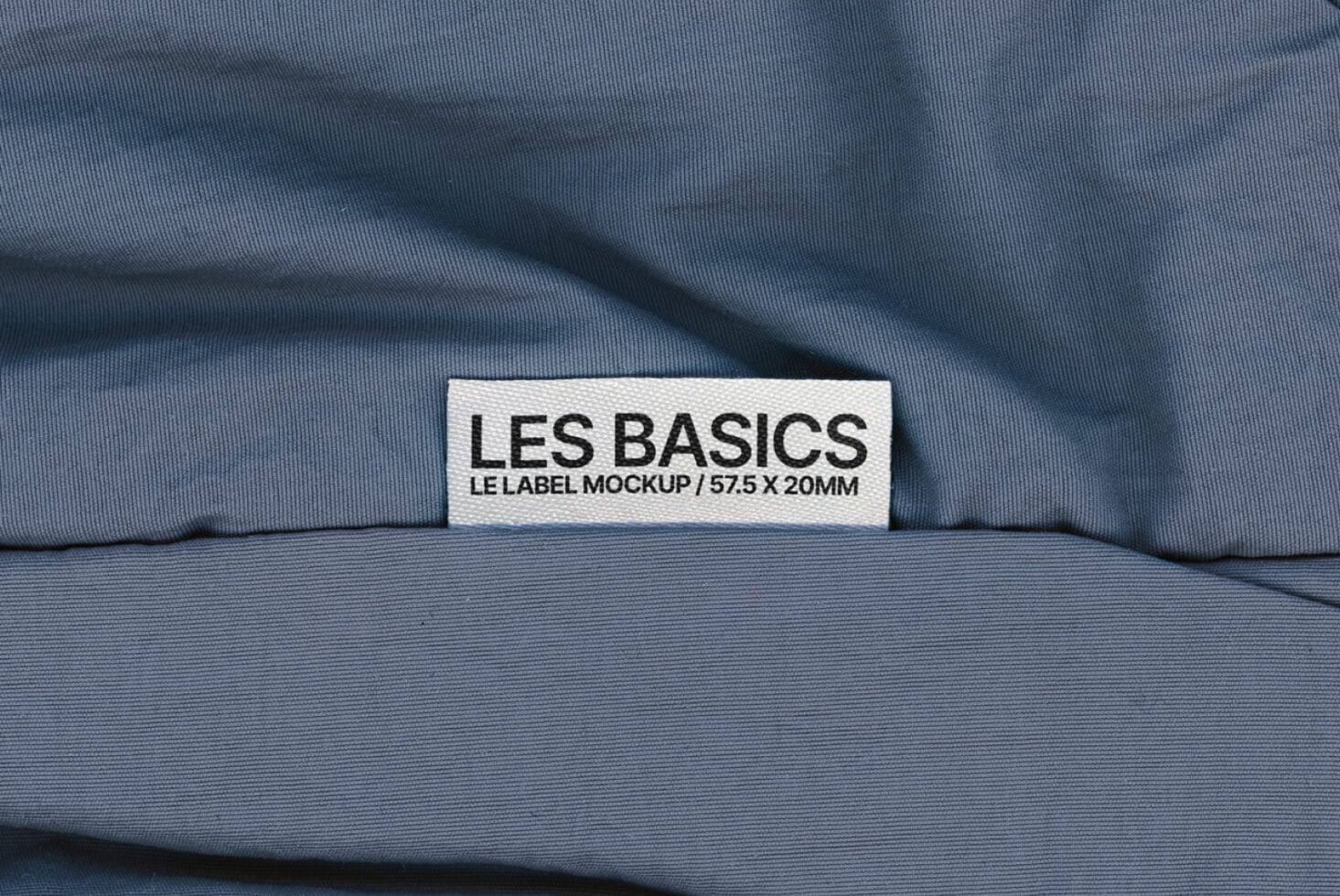 Les Basics woven tag on blue cloth with natural fold shadows