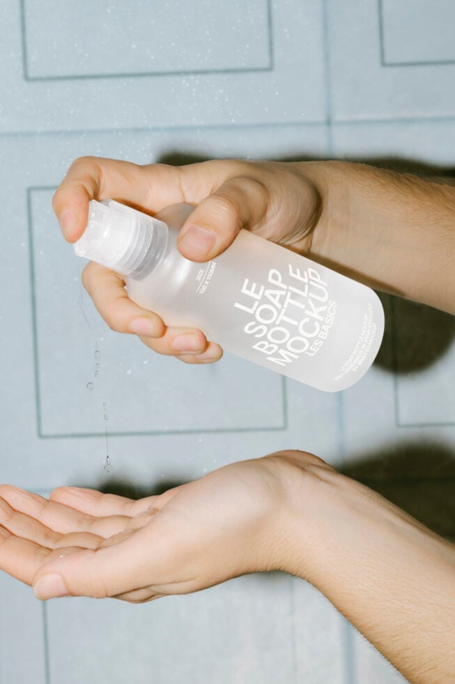 Hand holding white bottle with label text above open palm indoors
