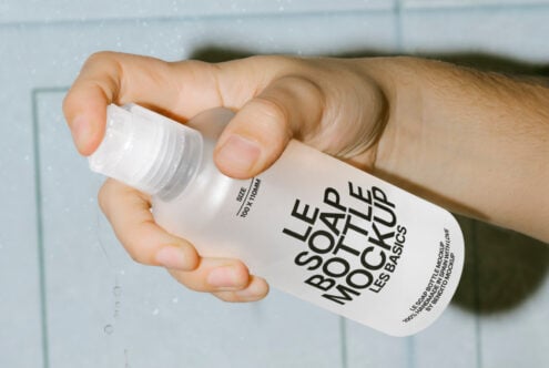 Hand holding a transparent soap bottle with label mockup, suitable for designers needing packaging templates. Keywords: mockup, soap bottle, template.