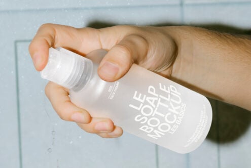Hand holding a clear spray bottle mockup with text overlay Le Soap Bottle Mockup. Ideal for designers in need of realistic product presentations.