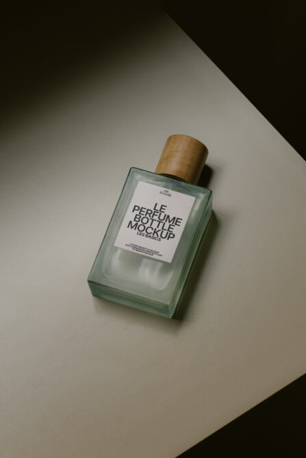Green glass perfume bottle mockup with white label on neutral surface