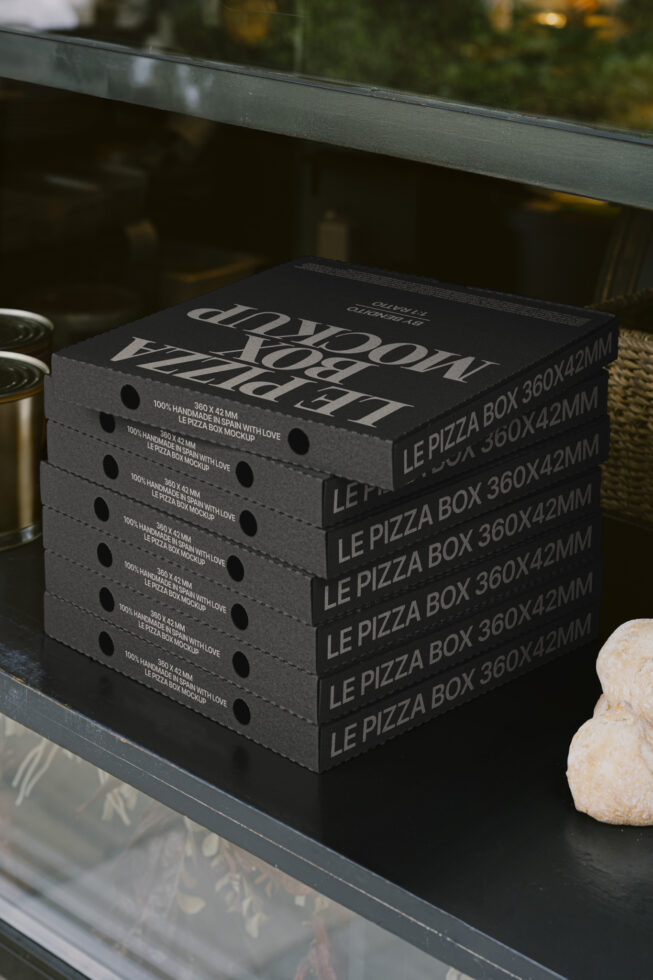 Stack of black pizza box mockups with white text on a countertop, ideal for packaging design, branding projects, graphic design templates, and presentations.