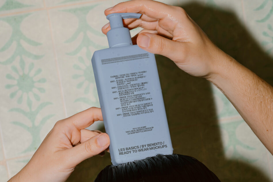Blue pump bottle held overhead showing full label design on leafy pattern backdrop