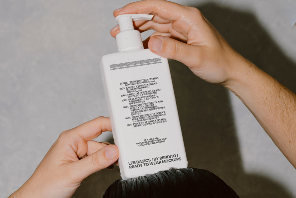 White soap bottle in hands with typography visible against neutral studio background