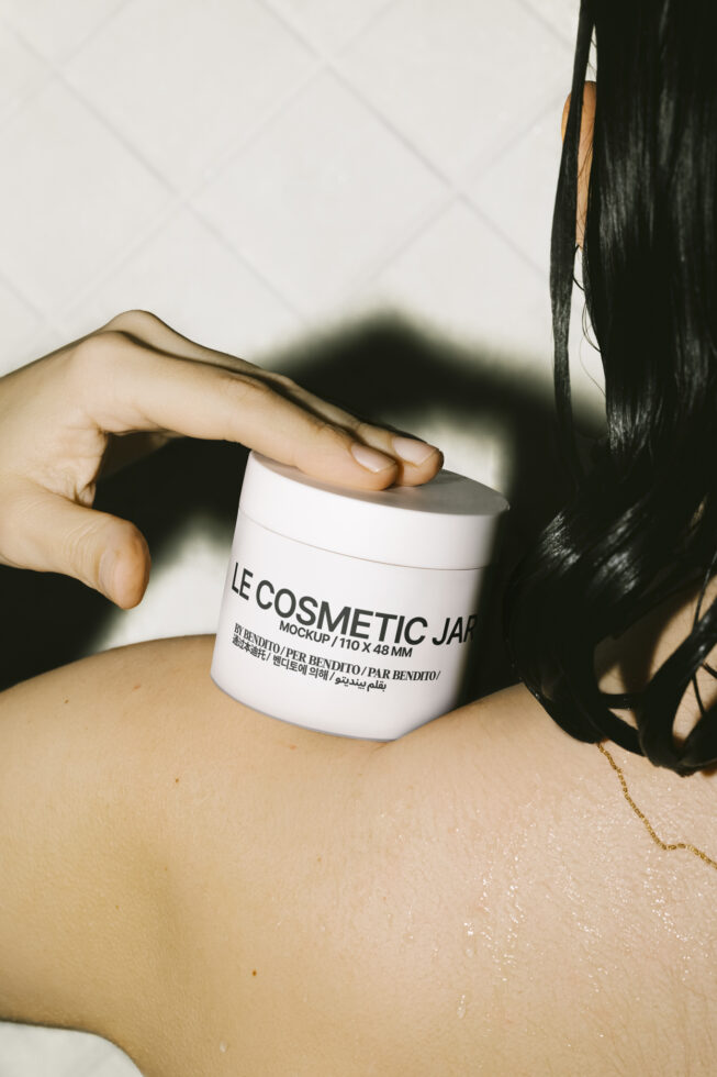 Cosmetic jar mockup held by hand on wet shoulder perfect for skincare packaging design templates graphic assets for designers high-quality PSD