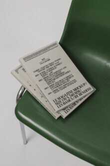 Stacked magazines with cream pages on dark green sculptural chair