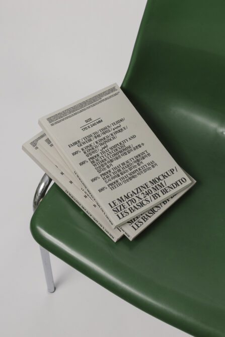 Stacked magazines with cream pages on dark green sculptural chair