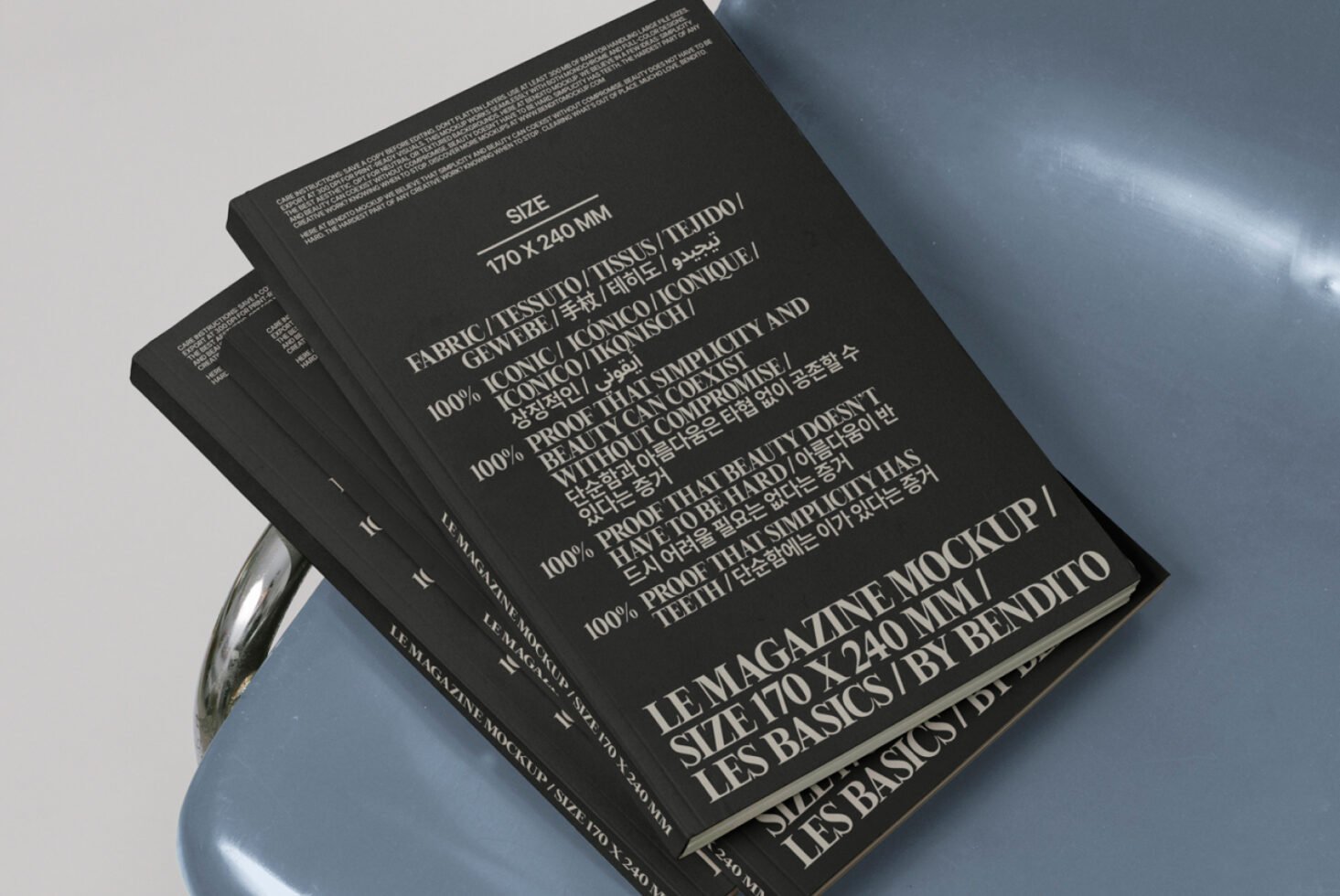 Black magazine mockup template featuring multilingual text on a gray chair. Ideal for designers seeking versatile print layout designs and presentations.