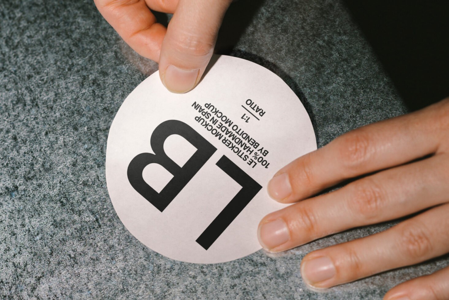 Close-up of hands applying a round sticker mockup on textured surface, showcasing 1:1 ratio. Ideal for designers seeking label and branding templates.