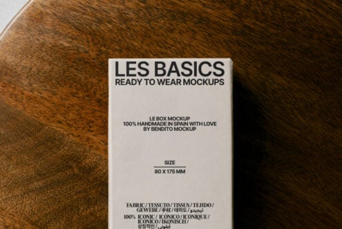Box mockup on wooden surface showcasing clean typography design. Text reads Les Basics Ready to Wear Mockups. Ideal for product mockup presentations.