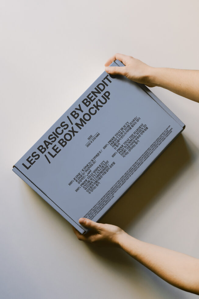Hands holding a minimalist box mockup with bold typography ideal for designers. Perfect for showcasing packaging designs in professional presentations.