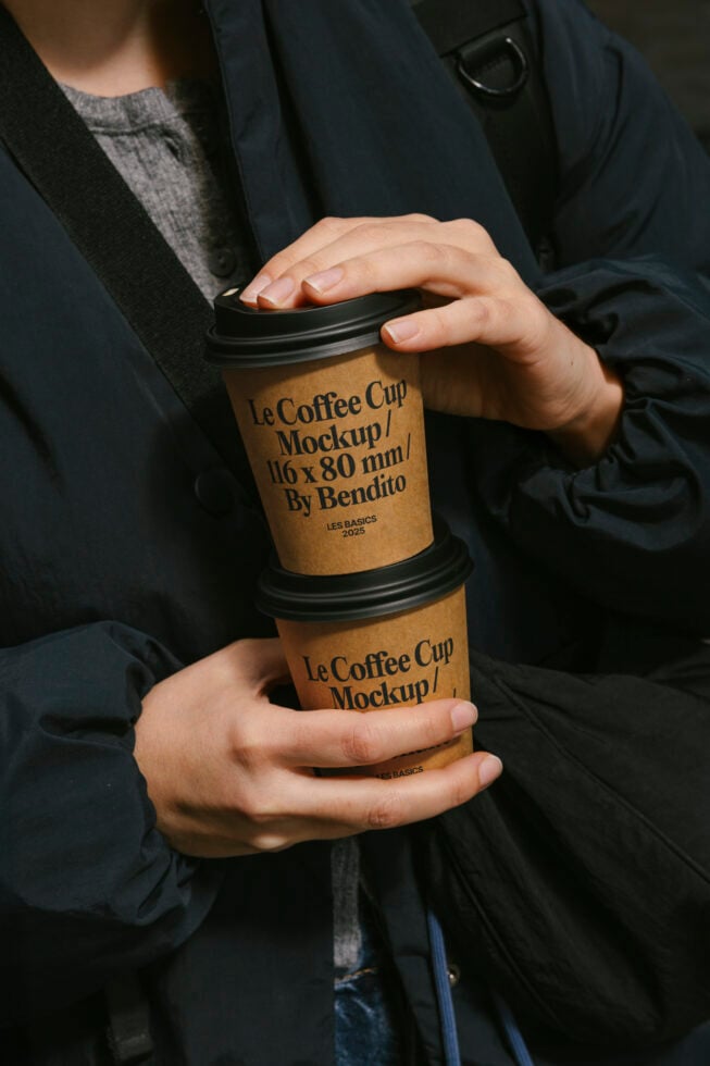 Person holds two Le Coffee Cup mockups in hands wearing a dark jacket design mockup branding template presentation packaging coffee cup graphic design.