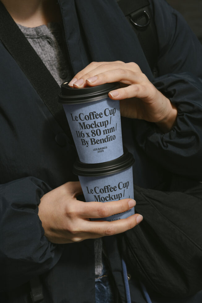 Person holding two blue coffee cup mockups with black lids labeled Le Coffee Cup Mockup by Bendito 2025 ideal for designers templates mockups graphics