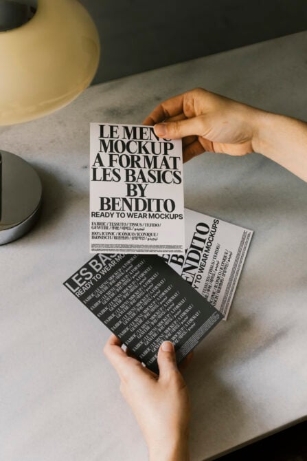 Hands holding white, black mockup sheets with ceramic bowls overhead on marble table