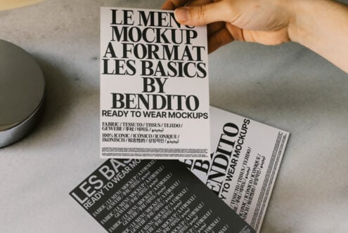 Designer holding fashion mockup flyers with bold fonts. Perfect for showcasing apparel or graphic templates. Ideal for creative professionals.