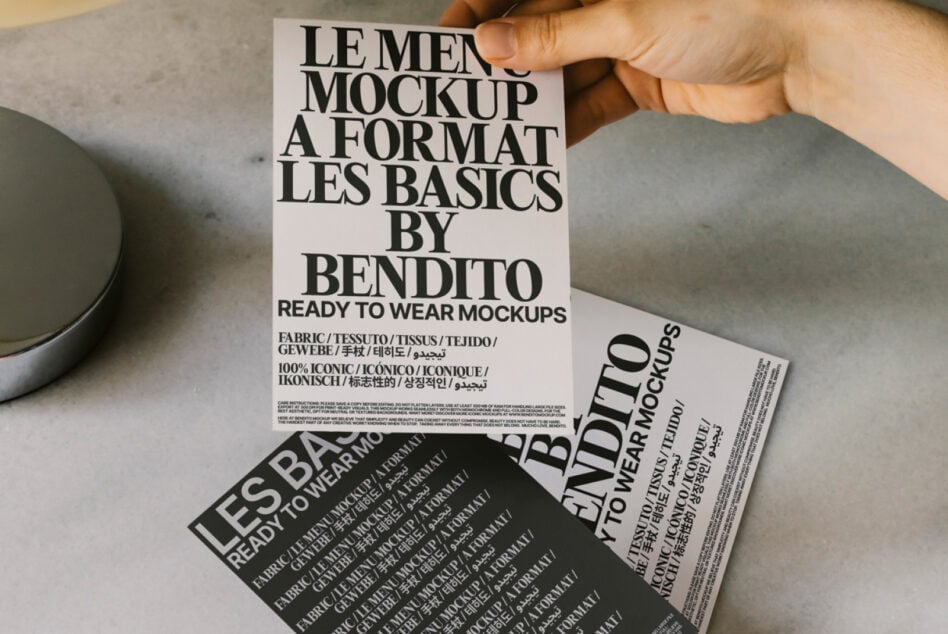 Flat lay of clothing tags with multilingual text, black coffee cups, ceramic bowls on neutral surface