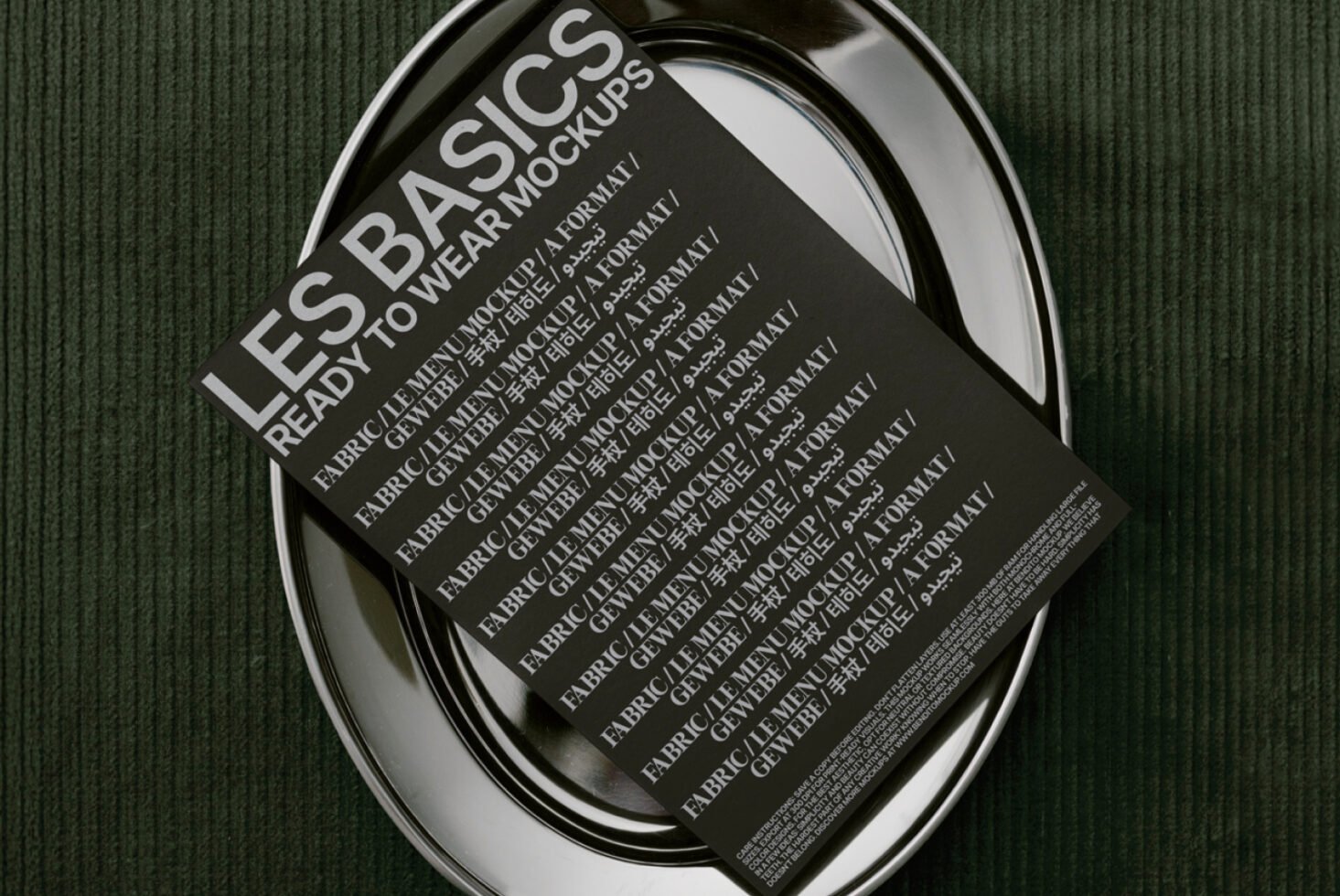 Mockup design featuring a black document on a metallic plate over green fabric background suitable for digital assets covers, ready-to-wear theme.